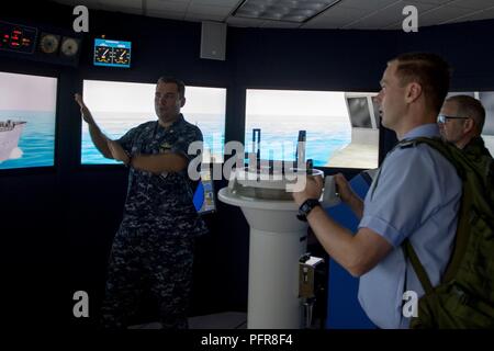 Everett, Washington. (21 maggio 2018) Lt. La Cmdr. Matt Farrell, delegato di Galla gruppo Formazione Pacific Northwest, spiega i compiti di un addetto conning a ufficiale dell'esercito tedesco, il Mag. Joachim Ruthe, in navigazione, marinaio e nave trainer di manipolazione nella stazione navale Everett (NSE). Ruthe e i suoi colleghi ufficiali sono iscritti in generale internazionale/Admiral personale corso ufficiale e sono touring NSE. Foto Stock