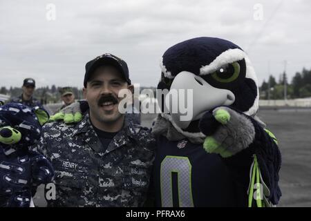 Nello stato di Washington (25 maggio 2018) Da elettricista, mate 1. Classe Giosuè Henry, da Gilchrist, Oregon, pone con Seattle Seahawks mascot, Blitz, a bordo della portaerei USS John C. Stennis (CVN 74). La Seattle Seahawks squadra di calcio e di mare galloni cheerleaders tenuto un apprezzamento militare evento a bordo per incontrare e parlare con i marinai. John C. Stennis è pier-lato dopo il ritorno a homeport dopo il completamento di un periodo di sette settimane in corso in cui l'equipaggio della nave completata TSTA/FEP precoce e Carrier Strike Gruppo 3 Gruppo Vela in preparazione per la sua prossima distribuzione programmata. Foto Stock