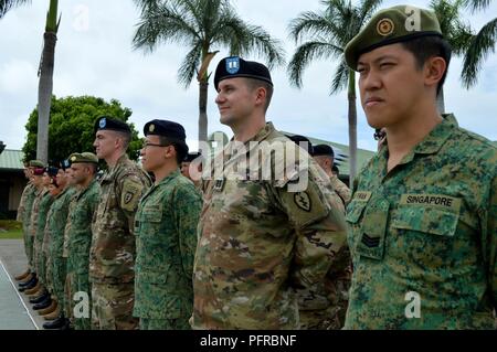 Stati Uniti I soldati assegnati al 3° Brigata Team di combattimento, XXV divisione di fanteria; la XXIX brigata di fanteria Team di combattimento, Hawaii esercito nazionale Guard 426th; gli affari civili battaglione, California Army National Guard e Singapore soldati assegnati al 6° Divisione, Esercito di Singapore e il decimo Singapore della brigata di fanteria ascoltare note conclusive durante la cerimonia di apertura di Tiger Balm 18 al 298reggimento, multifunzione unità di formazione (MFTU), regionale Training Institute (RTI), Waimanalo, Hawaii, il 26 maggio 2018. Tiger Balm è un bilaterale annuale di esercizio militare progettato per potenziare la professano Foto Stock