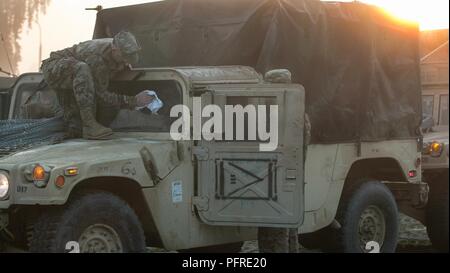 Chief Warrant Officer Zachary Wilkerson, (sinistra), un Black Hawk pilota di elicottero assegnati alla missione elemento di comando, 1a divisione di fanteria, Fort Riley, Kansas, salviettine la rugiada di mattina fuori il suo veicolo prima dell'inizio di un convoglio da Poznan, Polonia Bemowo Piskie Area Formazione, Polonia, 27 maggio 2018. Lo scopo del convoglio fu per spostare l'unità in tutta la Polonia e stabilire una Tactical Command Post (TAC) BPTA vicino a sostegno dell'imminente sciopero Saber esercizio. Sciopero di Saber 18, una multinazionale di esercizio prevista per il periodo da Giugno 3-15, prova i gruppi tattici eFP situato in Estonia, Lat Foto Stock