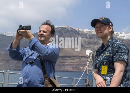 Della caldera di Santorini, Grecia (24 maggio 2018) - Ensign Nichole Roden, public affairs officer del guidato-missili cruiser USS Normandia (CG 60), parla con il Sig. Dimitris Prassos del vulcano di Santorini TV durante un tour a sostegno di una programmata visita porta. La Normandia è attualmente implementato come parte di Harry Truman Carrier Strike gruppo. Foto Stock