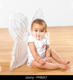 Una bambina vestita di bianco di ali di farfalla Foto Stock