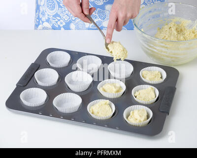 Spooning lime e cocco tortina miscela in casi la torta su un vassoio da forno Foto Stock