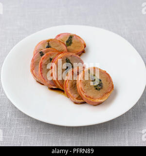 Filetto di maiale farcito con le olive e i peperoncini jalapeno, avvolto in pancetta servita su piastra bianca Foto Stock