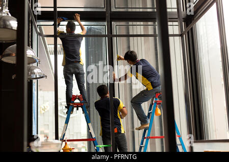 Lavoratore non identificato applicando lo strato colorato sul vetro della finestra Foto Stock