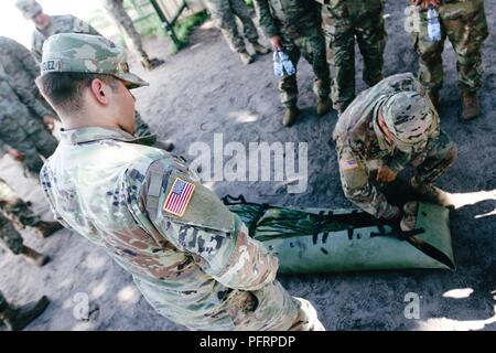 Sgt. Elias Rodriguez (centrale), Whittier, California native, combattere medic con il primo squadrone, 2° reggimento di cavalleria, supervisiona un soldato di preparare un incidente durante il combattimento ancora di salvezza la formazione con gruppo di combattimento della Polonia a Bemowo Piskie Area Formazione, Polonia, 30 maggio 2018. Gruppo di combattimento della Polonia è un luogo unico e multinazionale di coalizione di Stati Uniti, Regno Unito, croato e soldati rumeni che servono con il polacco della XV Brigata meccanizzata come una forza di dissuasione a sostegno della NATO in avanti rafforzata presenza. Foto Stock