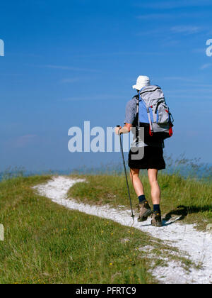 In Francia, gli escursionisti a piedi sul sentiero con un trekking pole, portando zaino e indossando un cappello per il sole Foto Stock