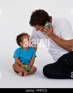 Padre e figlio giocando con i telefoni giocattolo Foto Stock