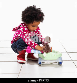 Il Toddler ragazza seduta bambola sul vasino portatile, 2 anni Foto Stock