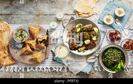 Pasto Libanese per la condivisione, compresi baba ganoush melanzana (DIP), fatayer bisabanikh (pasticceria pacchi), toum (salsa di aglio), Laban, djaj meshwi (pollo), khubz (pane), muhallabia (budino di latte), tabulé Foto Stock