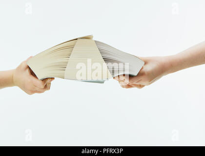 Bambini che cercano di tirare due libri con pagine interfogliate apart Foto Stock