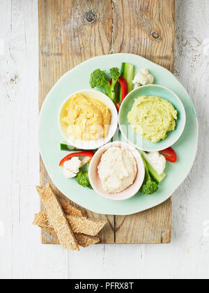 Hummus dips su una piastra con crudites vegetali (utilizzando TL vecchio pomodori, TR avanzi di avocado, B avanzi di fagioli) Foto Stock