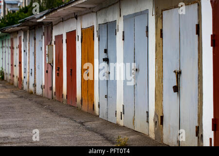 Fila di vecchio rosso bloccato le porte del garage con numeri, vista prospettica. Foto Stock