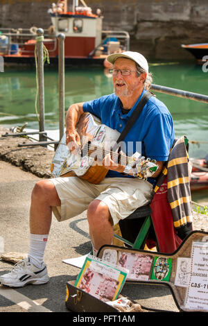 Regno Unito, Cornwall, Padstow, North Quay, fundraising busker Giovanni brezza a suonare la chitarra in aiuto di leucemia Busters carità Foto Stock