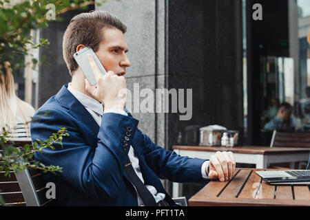 Giovani attraenti brunette imprenditore parla al telefono cellulare in cafe. Foto Stock