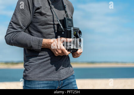 Persona in possesso di un retrò twin reflex fotocamera. Vicino alla cintura. Foto Stock