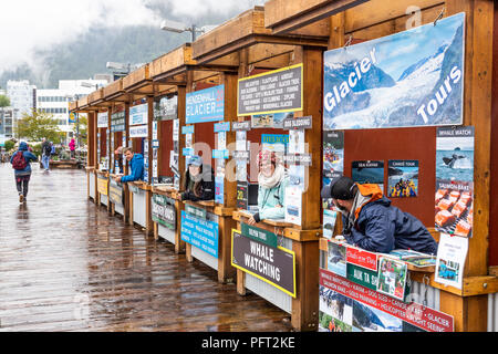 I tour operator si spera reclamizza per business su un piuttosto giorno piovoso nel porto di Juneau la città capitale di Alaska, STATI UNITI D'AMERICA Foto Stock