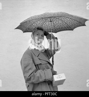 Anni Cinquanta donna con ombrello. Una giovane donna è in possesso di un ombrello in un giorno di pioggia. La Svezia 1955 Foto Stock