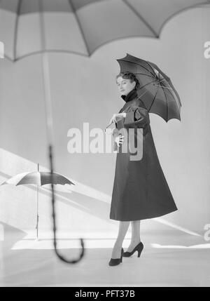 Anni Cinquanta la moda. Un giovane modello di moda in uno studio dove ella è indossare il cappotto moda dell'anno. La Svezia Marzo 1953 Foto Stock