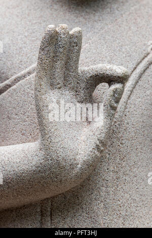 Primo piano della mano destra del Buddha scolpita in pietra, simbolismo pacifico dell'arte e della spiritualità buddista tradizionali, simbolismo buddista Foto Stock