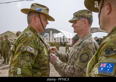 Stati Uniti Esercito il Mag. Gen. Walter Piatt, vice comandante della transizione della Combined Joint Task Force - Funzionamento inerenti risolvere promuove l'esercito australiano garantisce Officer Classe 2 Kenneth Roberts, del Task Group Taji, per giustificare Officer Classe 1 durante una transizione di indirizzo per l'Australia, la Nuova Zelanda e il Regno Unito di militari del Task Group Taji VI e VII a Camp Taji, Iraq, 24 maggio 2018. Più di 300 Australiano e 100 Nuova Zelanda il personale militare sono dispiegati in Iraq come parte del Task Group Taji VI. Lo scopo della missione è di addestrare i membri delle forze di sicurezza irachene come continuano Foto Stock