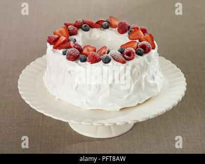 Angel food cake guarnita con frutti di bosco torta sul supporto Foto Stock