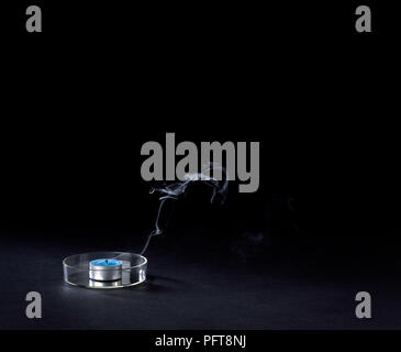 Il fumo proveniente da spenta tealight su sfondo nero Foto Stock