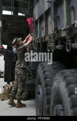 Un Marine aiuta i bambini di un mezzo tattico di sostituzione del veicolo 7-ton 6x6 durante la settimana della flotta di New York al Liberty State Park in Jersey City, N.J., 27 maggio, 2018. Il MTVR 7-ton 6x6 è stato uno dei tre veicoli sul display a Liberty State Park. Foto Stock