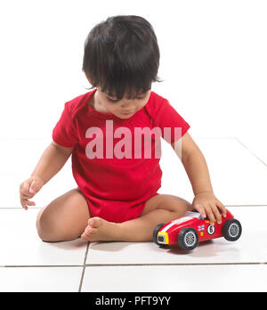 Baby boy (16 mesi) seduta giocando con il giocattolo auto Foto Stock