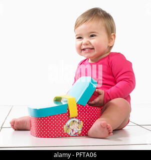 Baby girl (12 mesi) seduto a giocare con il giocattolo Cesto picnic Foto Stock