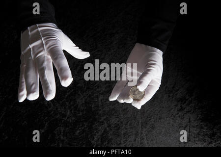 In guanti bianchi e mani coin Foto Stock