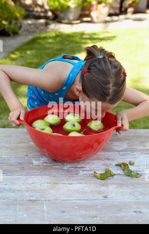 Ragazza che gioca apple bobbing gioco Foto Stock