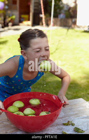 Ragazza che gioca apple bobbing gioco Foto Stock