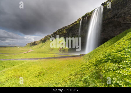 Una tempesta vista estiva della bella cascata Seljalandsfoss, un popolare stop sull'Islanda Golden Circle itinerario turistico. Foto Stock