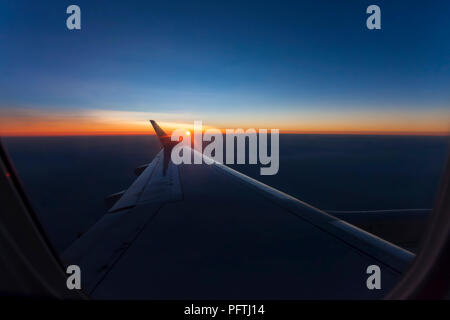 Rosa alba luce sulla nuvola sotto l'ala di aeroplano Foto Stock