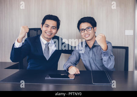 Gli imprenditori asiatici il successo e il concetto vincente - happy team con alzata fino a mani celebra la conquista e realizzazioni Foto Stock