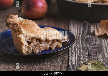 Torta di mele con fetta rimosso e mele fresche sulla tavola in legno rustico Foto Stock