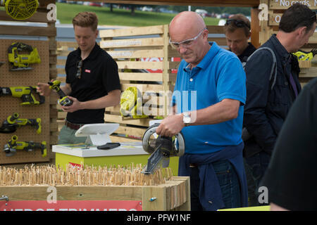 Persone che guardano gli strumenti di vendita & man utilizzando cordless tosasiepi - Ryobi stand commerciali, RHS Chatsworth Flower Show, Derbyshire, Inghilterra, Regno Unito. Foto Stock