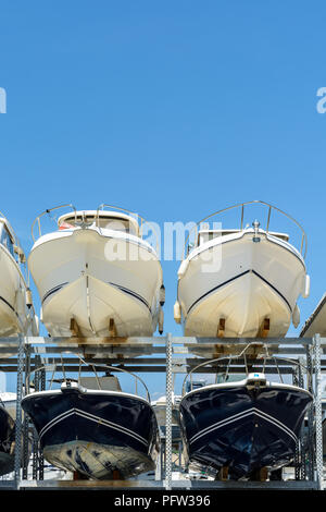 Vista dal basso degli scafi di barche a motore con rack uno sopra l'altro su due livelli in un rack a secco imbarcazione impianto di stoccaggio contro il cielo blu. Foto Stock