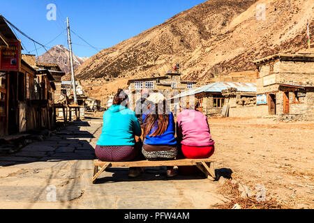 Manang, Nepal - Novembre 11, 2015: tre donne nepalesi seduto sul banco in strada nel villaggio di montagna Manang, Himalaya Foto Stock