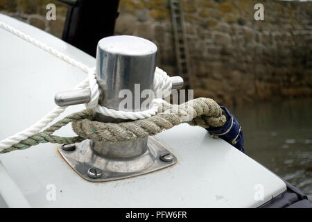 Funi legate attorno ad un gancio o bollard su una piccola barca ormeggiata in un porto Foto Stock