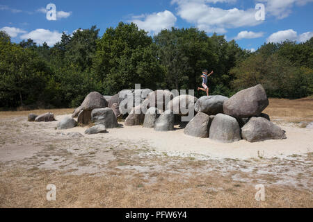 Havelte, Drenthe, Paesi Bassi - 14 Luglio 2018: bambino saltando sulle pietre di una vecchia tomba di pietra come un grande dolmen in Drenthe Olanda, chiamato in olandese Foto Stock