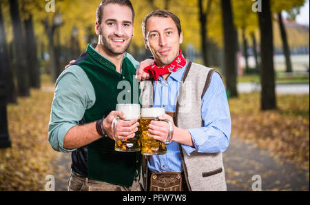 Gli uomini in bayrischer Tracht tintinnanti bicchieri di birra Foto Stock