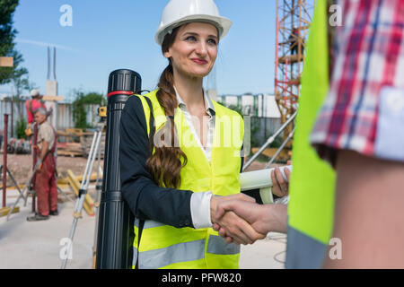 Architetto e ingegnere o supervisore stringono le mani sul sito in costruzione Foto Stock