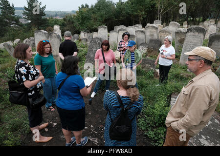 I partecipanti dell'agenzia turistica ROOTKA, specializzata in tour del patrimonio ebraico nell'Europa orientale, si trovano in mezzo a vecchie lapidi del cimitero ebraico che si estende su una collina sopra la città di Buchach, che un tempo era sede di una grande comunità ebraica e fu annientata, brutalmente, Dai tedeschi durante la seconda guerra mondiale a Ternopil Oblast (provincia) nell'Ucraina occidentale. Foto Stock