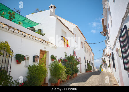 Camminando su di una tranquilla strada stretta di case bianche con vasi di fiori e di belle piante in Mijas Andalusia Spagna in una giornata di sole Foto Stock