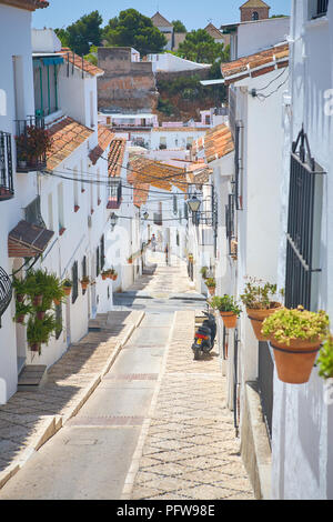 Ciclista al fondo di una ripida stretta strada tradizionale di pretty bianco Case Murate in Mijas, Andalusia Spagna Foto Stock