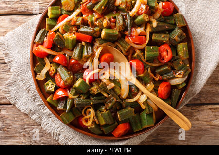 Un sano pasto dietetico okra con pomodoro e cipolla close-up su una piastra sul tavolo. Parte superiore orizzontale vista da sopra Foto Stock