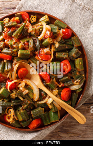 Un sano pasto dietetico okra con pomodoro e cipolla close-up su una piastra sul tavolo. Verticale in alto vista da sopra Foto Stock