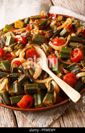 L'okra fritte con pomodoro e cipolla close-up su una piastra sul piano verticale. Foto Stock